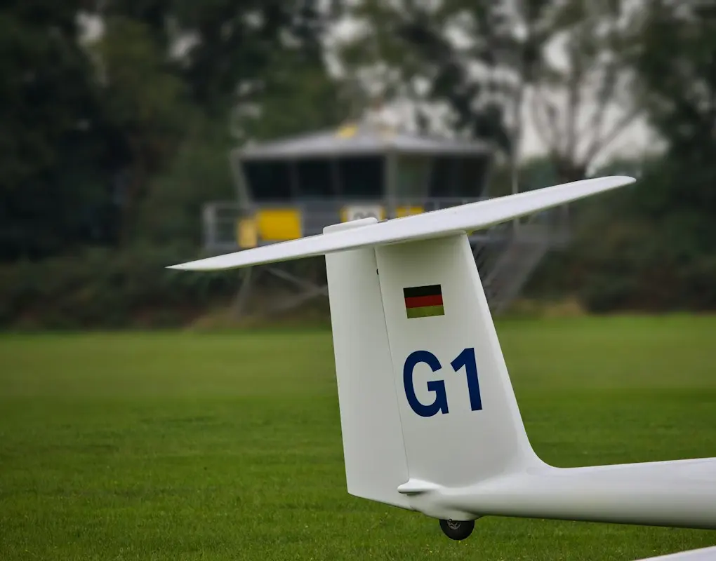 Seitenleitwerk eines Segelflugzeugs mit deutscher Flagge auf einem Grasplatz